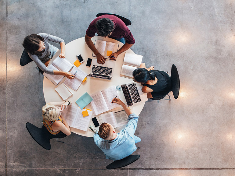 Blick aus Vogelperspektive auf einen runden Tisch, an dem fünf Studierende arbeiten